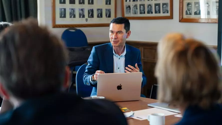 Lyndon Drake at a desk talking to meeting attendees